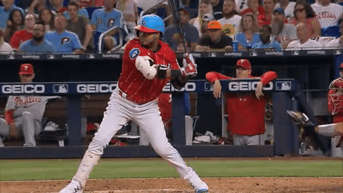 A Baseball Player Getting Ready To Swing At A Pitch With A Geico Banner Behind Him GIF
