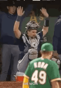 A Baseball Player In A Green Jersey Is Giving A High Five To Another Player . GIF