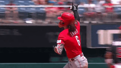 A Baseball Player In A Red Uniform Is Running Towards The Base . GIF
