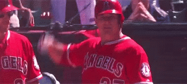 A Baseball Player In A Red Uniform Is Swinging A Bat At A Ball In A Dugout . GIF