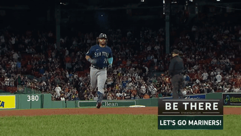 A Baseball Player In A Seattle Uniform Is Running Towards A Sign That Says Be There Let 'S Go Mariners GIF