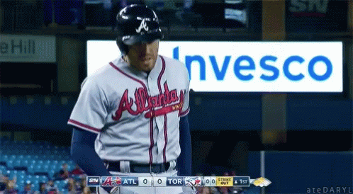a baseball player in an atlanta braves uniform stands in front of a sign for invesco