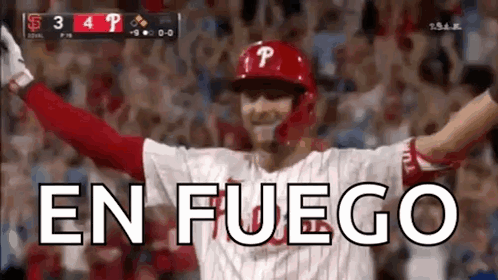 A Baseball Player Is Celebrating With His Arms In The Air And The Word En Fuego Is Visible In The Background . GIF
