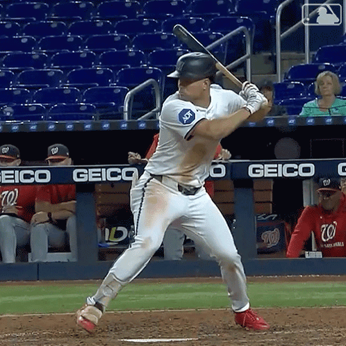 A Baseball Player Is Getting Ready To Swing At A Pitch In Front Of A Geico Banner GIF