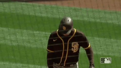 A Baseball Player Is Holding A Bat And Smiling On The Field . GIF
