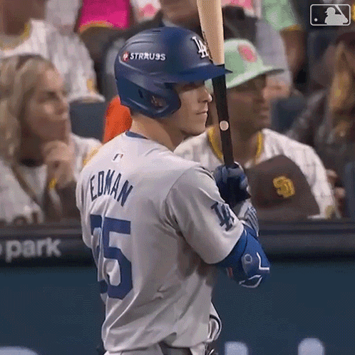 A Baseball Player Is Holding A Bat And Wearing A Helmet With The Letter L On It . GIF