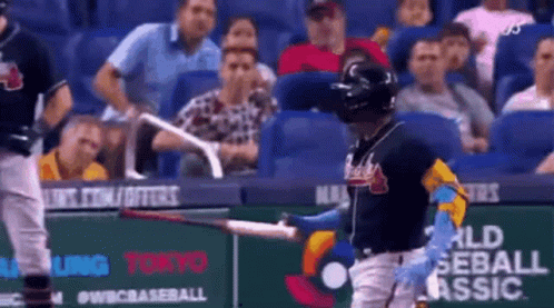 A Baseball Player Is Holding A Bat In Front Of A Crowd Of People In A Stadium . GIF