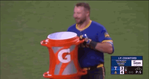 A Baseball Player Is Holding A Gatorade Bucket On The Field . GIF