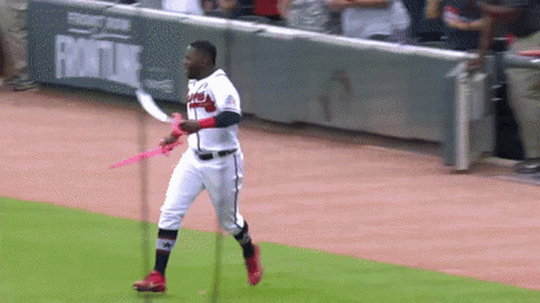 A Baseball Player Is Holding A Pink Ribbon On A Baseball Field GIF