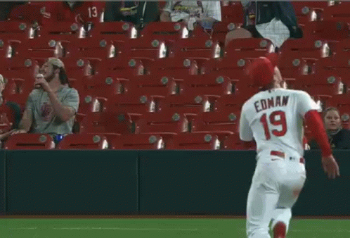 A Baseball Player Is Laying On The Field While A Fan Watches . GIF
