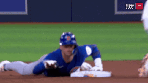 A Baseball Player Is Laying On The Ground On The Field . GIF