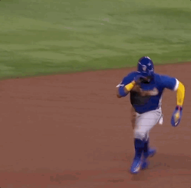 A Baseball Player Is Laying On The Ground While A Referee Watches . GIF