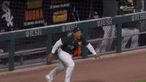 A Baseball Player Is Running On The Field In Front Of A Banner For Buona GIF