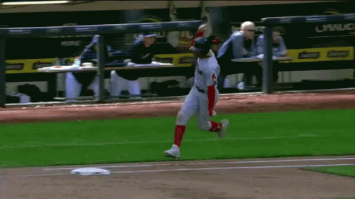 A Baseball Player Is Running On The Field With A Dugout In The Background That Says Corona GIF