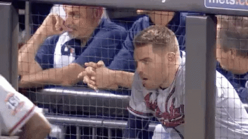 A Baseball Player Is Shaking Hands With A Fan While Sitting In The Dugout . GIF