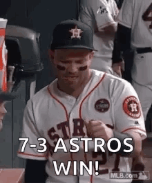 A Baseball Player Is Sitting In The Dugout With His Fist In The Air And Says `` 7- 3 Astros Win '' . GIF
