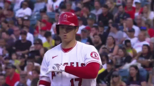 A Baseball Player Is Standing In Front Of A Crowd While Wearing A Helmet . GIF
