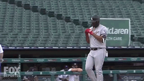 A Baseball Player Is Standing In Front Of A Green Sign That Says Mclaren Healthcare GIF