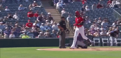 A Baseball Player Is Standing On A Baseball Field With A Referee Standing Behind Him . GIF