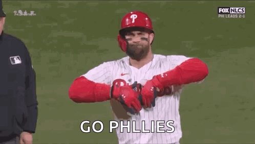 A Baseball Player Is Standing On A Field With His Arms Crossed And A Referee Behind Him . GIF