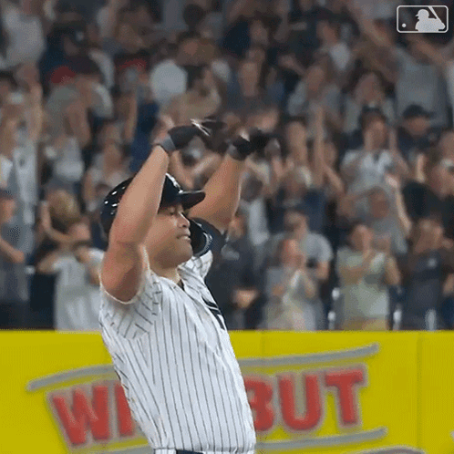 A Baseball Player Is Standing On The Field With His Arms In The Air GIF