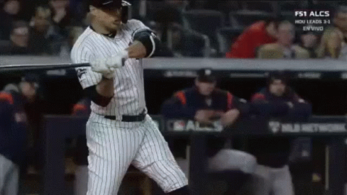 A Baseball Player Is Swinging A Bat At A Ball In A Baseball Game . GIF