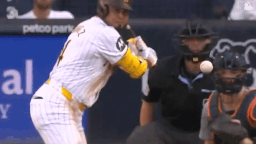 A Baseball Player Is Swinging A Bat At A Ball While A Catcher Watches GIF