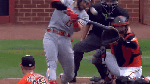 A Baseball Player Is Swinging A Bat At A Ball While The Catcher Watches GIF
