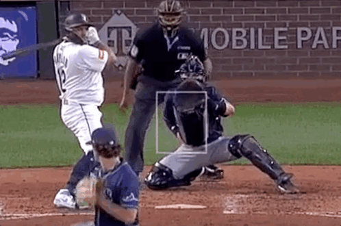 A Baseball Player Is Swinging A Bat At A Pitch While A Catcher Is Sitting On The Base . GIF