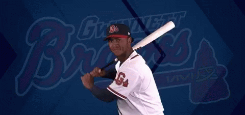 A Baseball Player Is Swinging A Bat In Front Of A Giant Night Brewers Logo GIF
