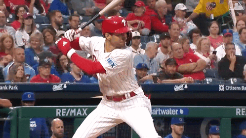 A Baseball Player Is Swinging A Bat In Front Of A Re / Max Banner GIF