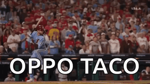 A Baseball Player Is Swinging At A Ball In Front Of A Crowd . GIF