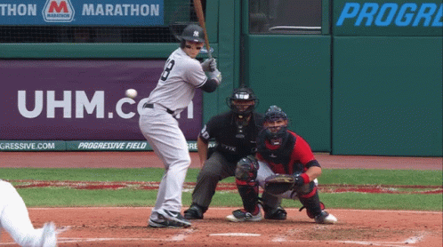 A Baseball Player Is Swinging At A Ball In Front Of An Uhm.com Banner GIF
