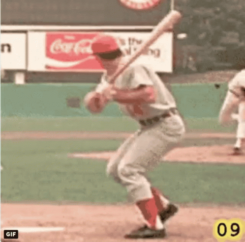 A Baseball Player Is Swinging At A Ball With A Coca Cola Sign In The Background GIF