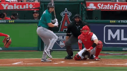 A Baseball Player Is Swinging His Bat At A Ball In Front Of A State Farm Ad GIF