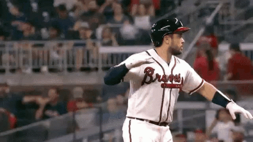 A Baseball Player Is Swinging His Bat At A Ball While Standing On The Field . GIF