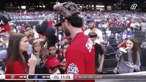 A Baseball Player Is Talking To A Woman In The Stands During A Game . GIF