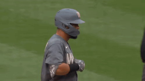 a baseball player is talking to an umpire while wearing a helmet .