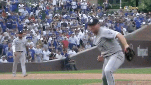 A Baseball Player Is Throwing A Ball To Another Player On A Field . GIF