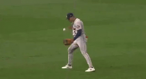 A Baseball Player Is Trying To Catch A Ball On A Field . GIF