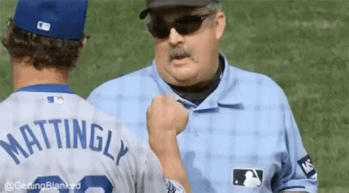 A Baseball Player Named Mattingly Is Shaking Hands With A Referee . GIF