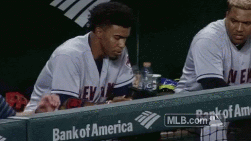 A Baseball Player Sits In The Dugout With A Bank Of America Ad Behind Him GIF