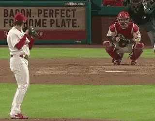a baseball player stands in front of a bacon perfect home plate sign