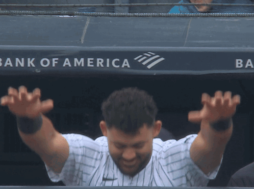 A Baseball Player Stands In Front Of A Bank Of America Sign GIF