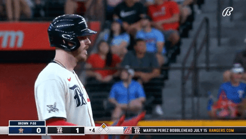 A Baseball Player Stands In Front Of A Scoreboard That Says Rangers.com GIF