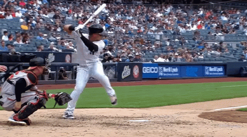 A Baseball Player Swings His Bat At A Pitch In Front Of A Sign For Geico GIF