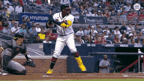 A Baseball Player Swings His Bat At A Pitch While A Catcher Looks On GIF