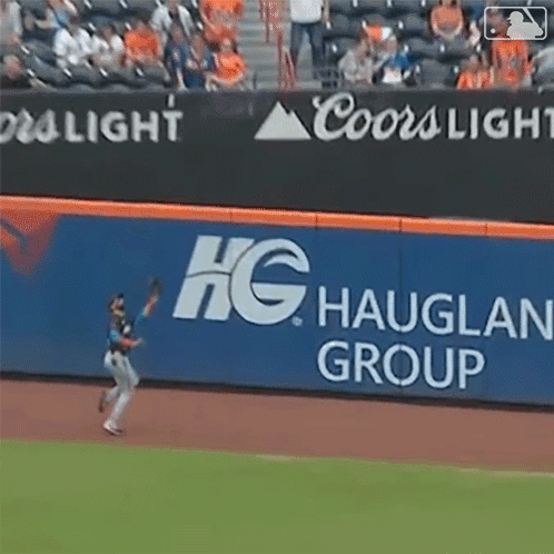 A Baseball Player Throws A Ball In Front Of A Coors Light Sign GIF