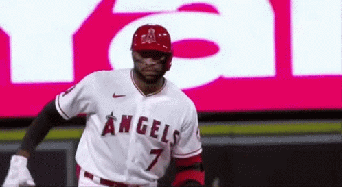 A Baseball Player Wearing A Angels Jersey Is Standing In Front Of A Large Screen . GIF