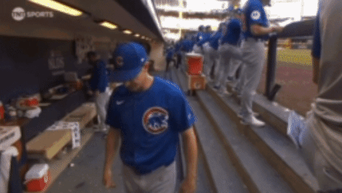 a baseball player wearing a blue cubs shirt walks down the stairs